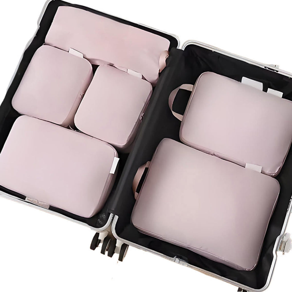 Packing cubes in roze: zes packing cubes plat in een open koffer, van bovenaf gezien