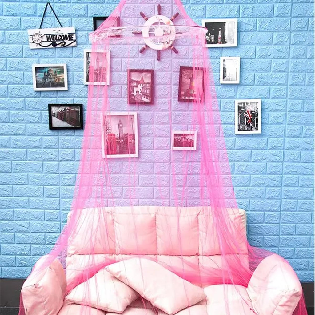 Roze klamboe boven een roze bank, het net ligt in een grote cirkel op de vloer voor een blauwe bakstenen muur