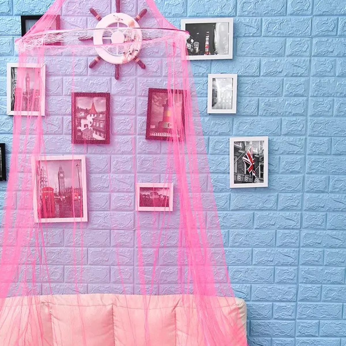 De bovenkant van de roze klamboe met de ring en de witte kanten rand voor een muur met fotolijstjes