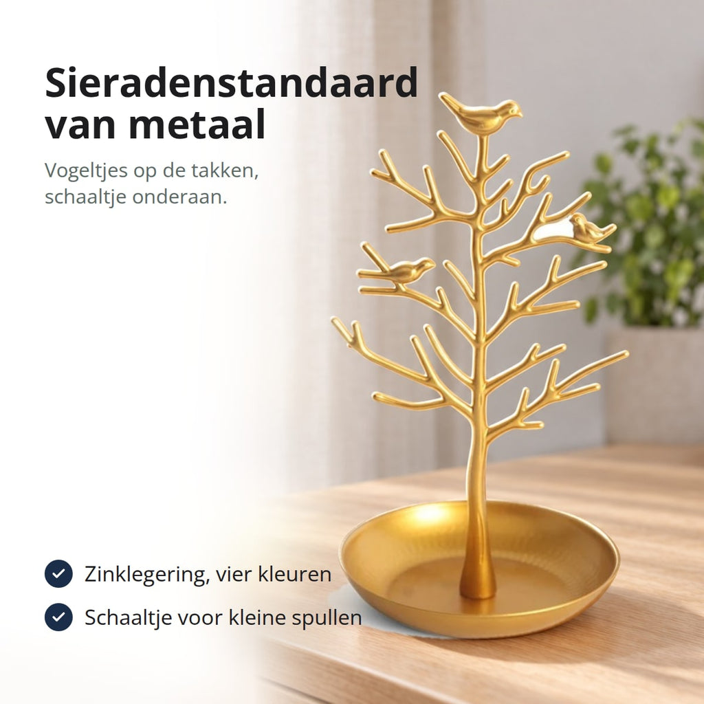 Sieradenstandaard van goudkleurig metaal met vogeltjes en schaaltje op een ladekast, met de tekst: zinklegering in vier kleuren, schaaltje onderaan voor kleine spullen