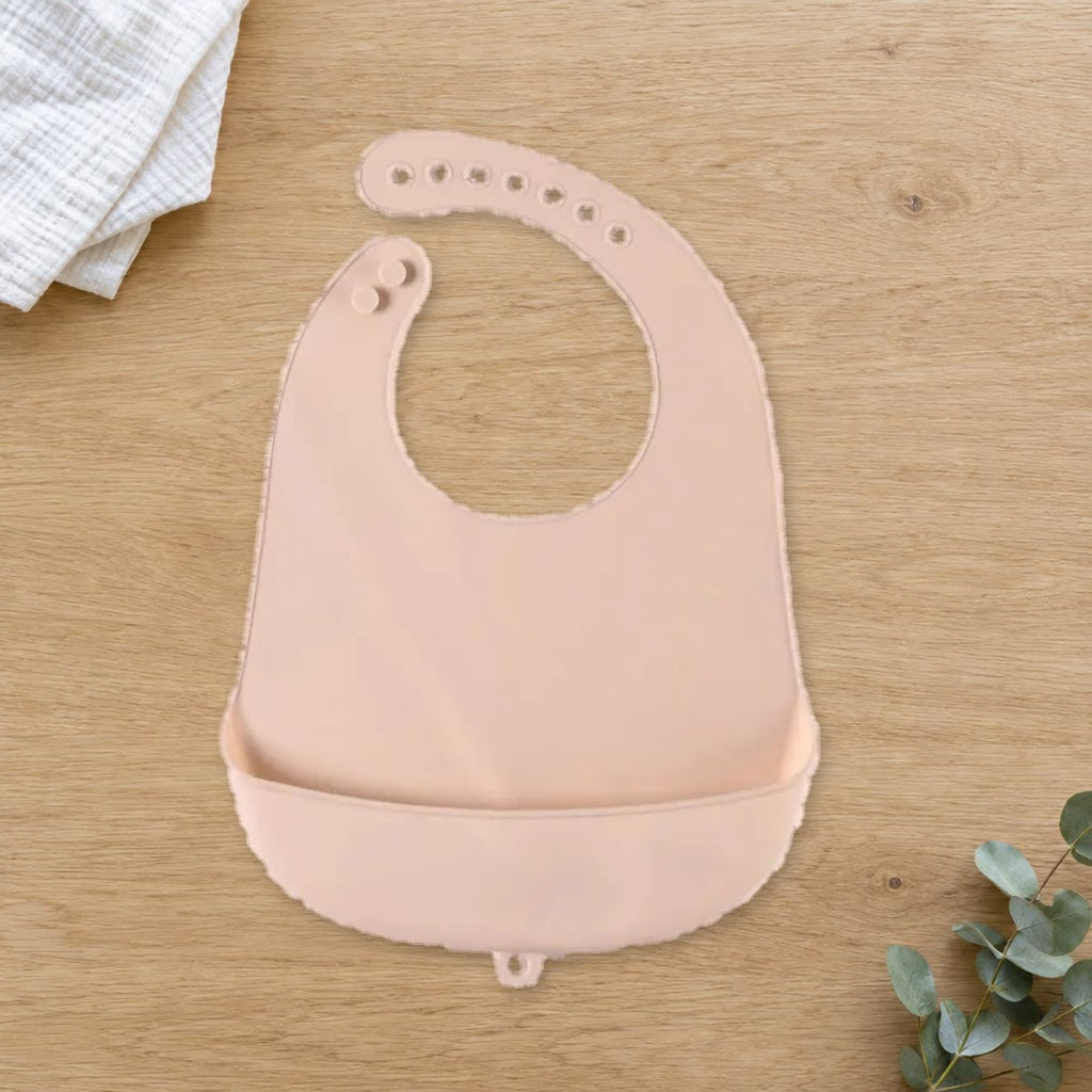 Beige siliconen slabbetje met opvangbakje op een eikenhouten tafel