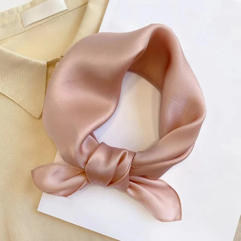 Kleine roze zijden sjaal, met een strik geknoopt op een lichte blouse