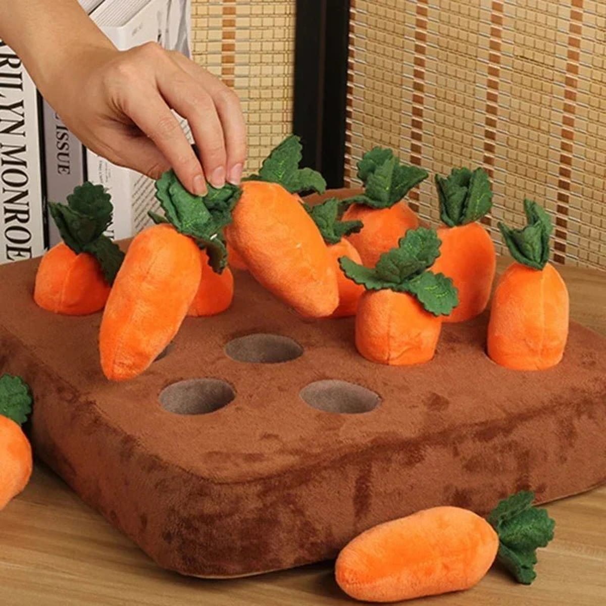 Een hand die een pluche wortel uit de snuffelmat trekt