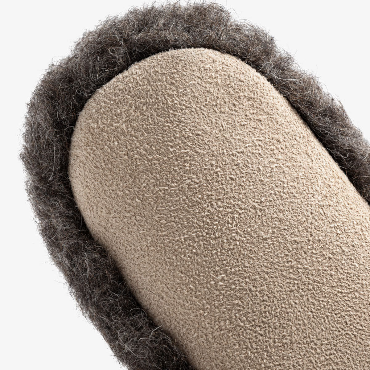 Close-up van de leren zool onder de donkergrijze wollen pantoffel