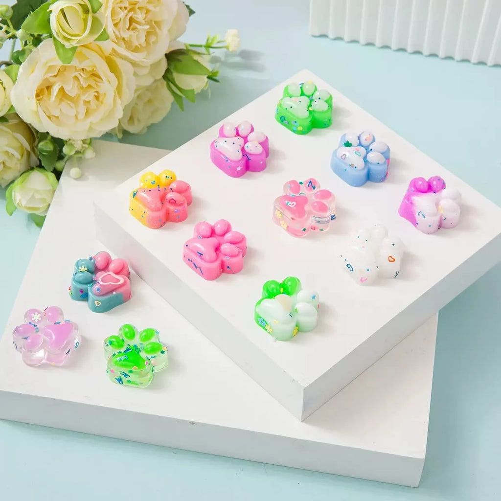 Squishy kattenpootjes in pastelkleuren op een wit podium met bloemen