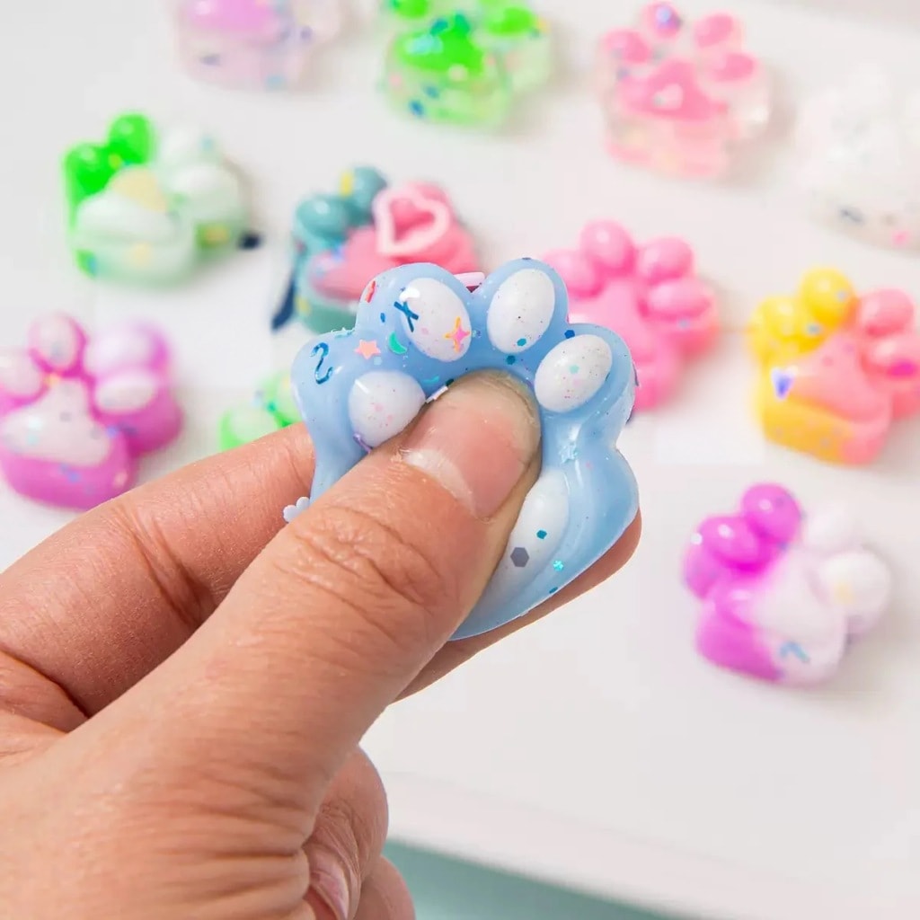 Een hand knijpt in een blauw squishy kattenpootje