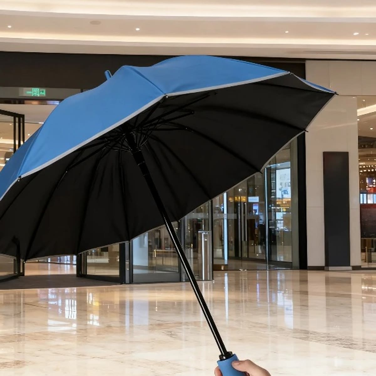 Blauwe stormparaplu met zwarte binnenkant en reflectie langs de rand, binnenshuis omhoog gehouden