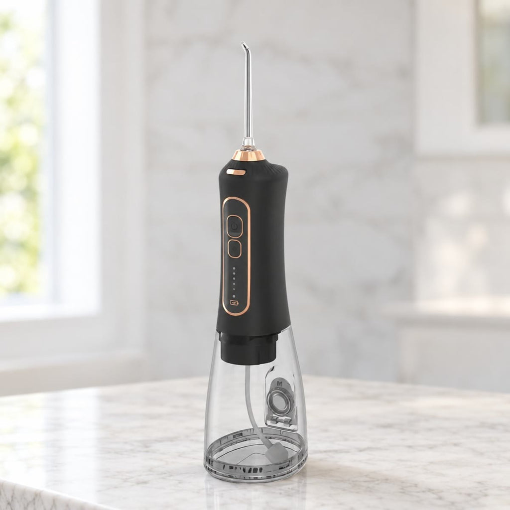 Zwarte draadloze waterflosser met goudkleurige ring en doorzichtig waterreservoir op een marmeren blad