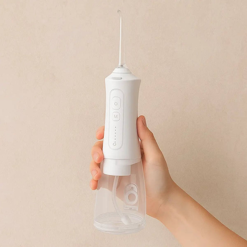 Hand houdt de witte waterflosser vast tegen een beige achtergrond