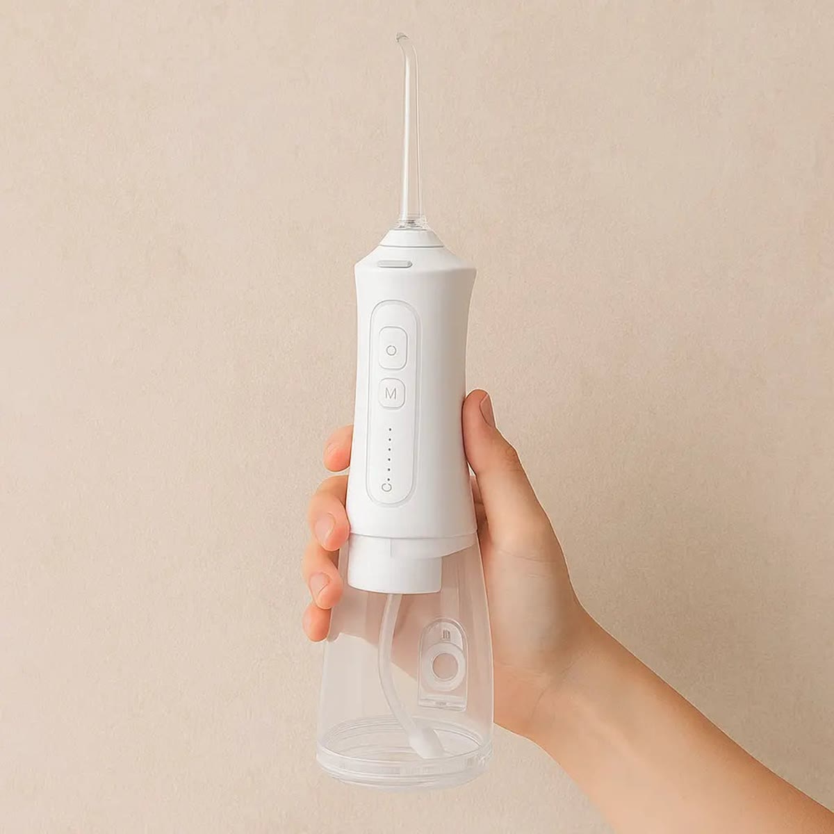 Hand houdt de witte waterflosser vast tegen een beige achtergrond
