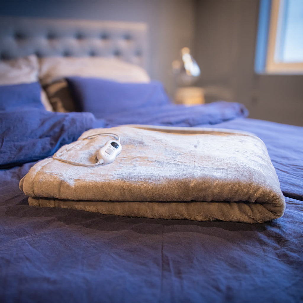 De warmtedeken opgevouwen op bed met de bediening erbovenop