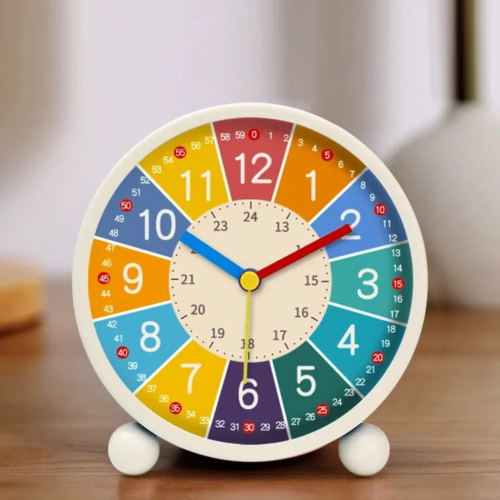De kinderwekker met witte rand en twee kleine pootjes op een houten tafel, met een lichte woonkamer op de achtergrond