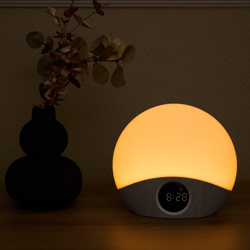De wekker met warm licht naast een zwarte vaas met eucalyptus