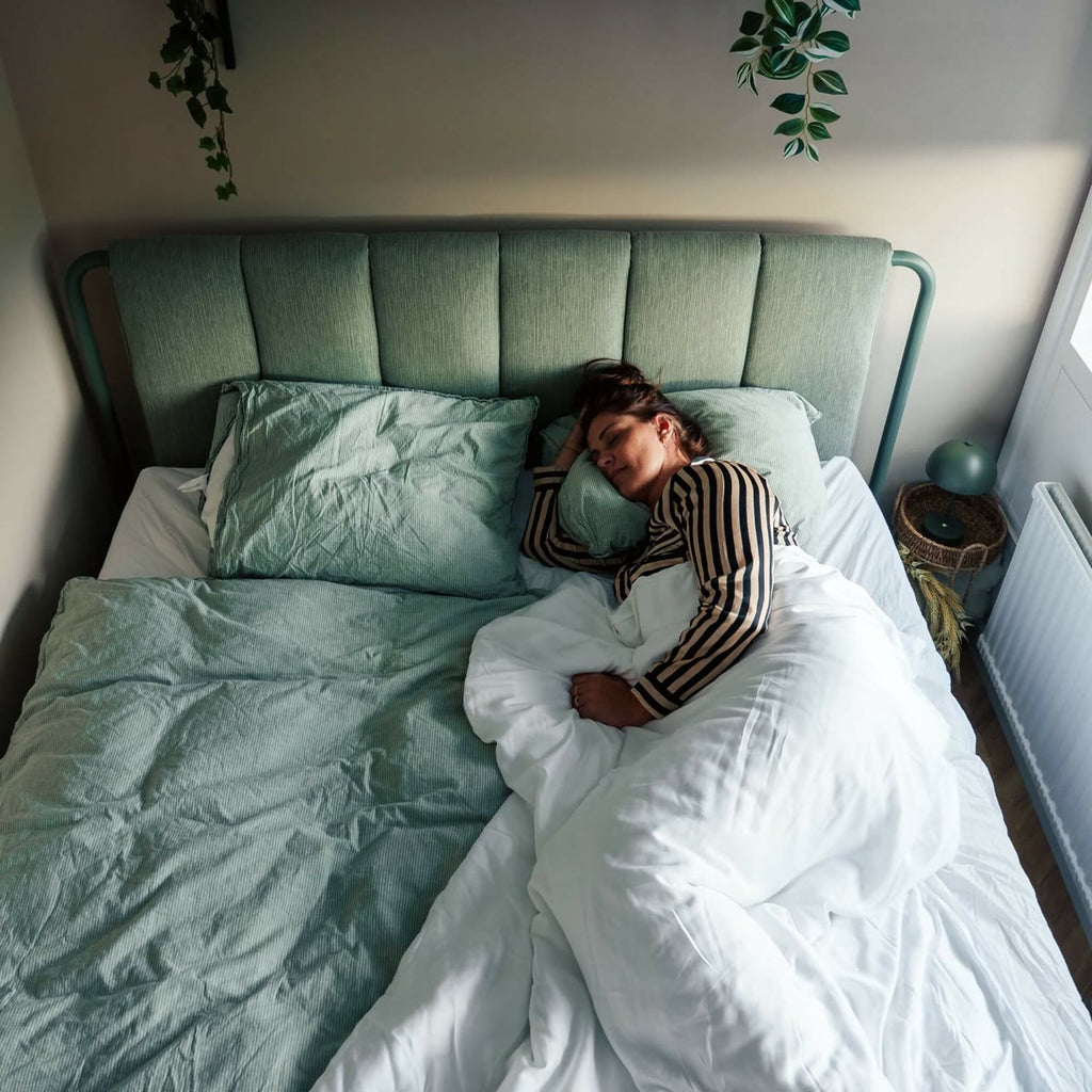 De verzwaringsdeken uitgespreid over het bed met een slapende vrouw, van bovenaf gezien