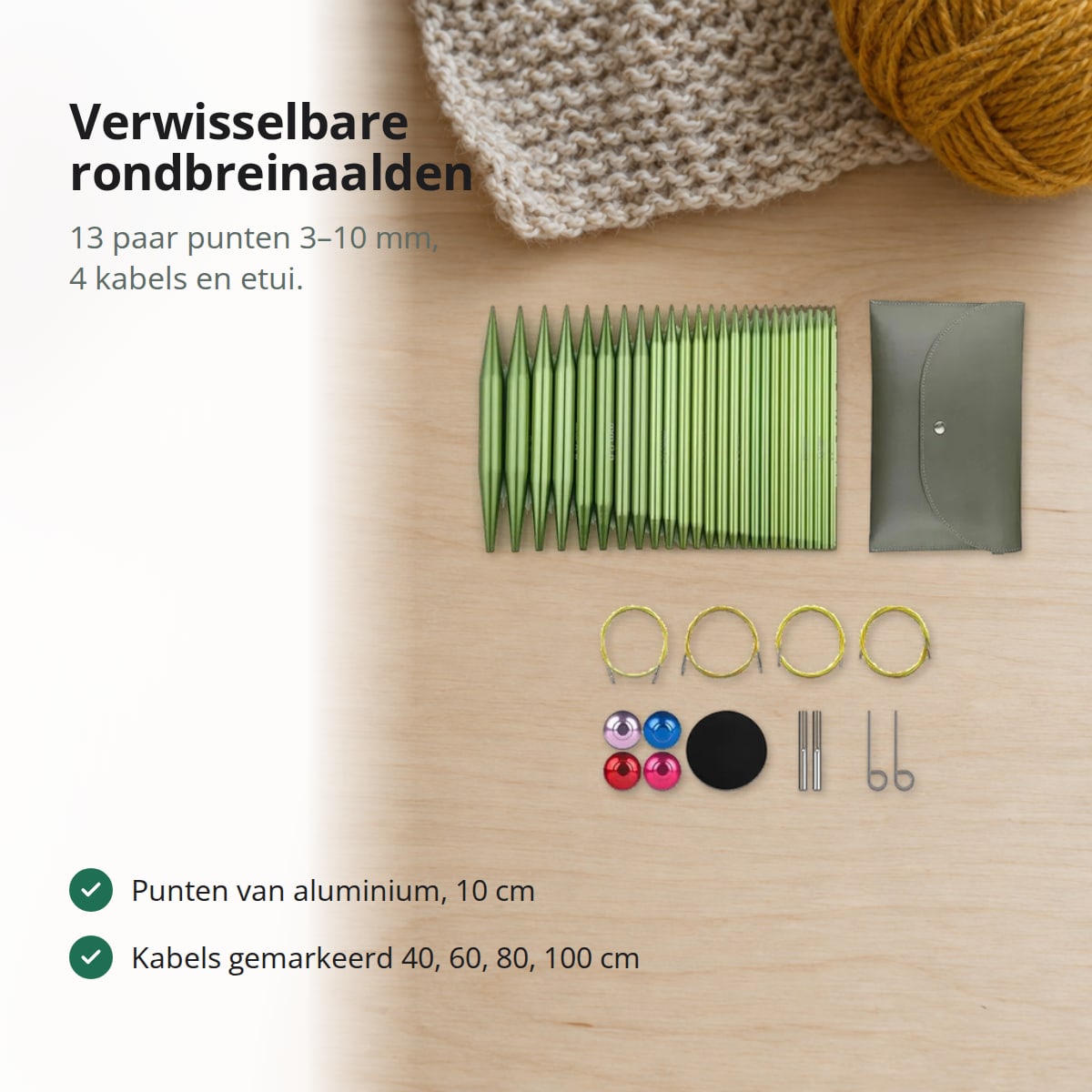 Verwisselbare rondbreinaalden van groen aluminium met vier kabels, eindstoppers, sleuteltjes en etui op een lichte tafel met bollen garen, met de tekst: verwisselbare rondbreinaalden, 13 paar punten 3–10 mm, 4 kabels en etui, punten van aluminium van 10 cm, kabels gemarkeerd met 40, 60, 80 en 100 cm