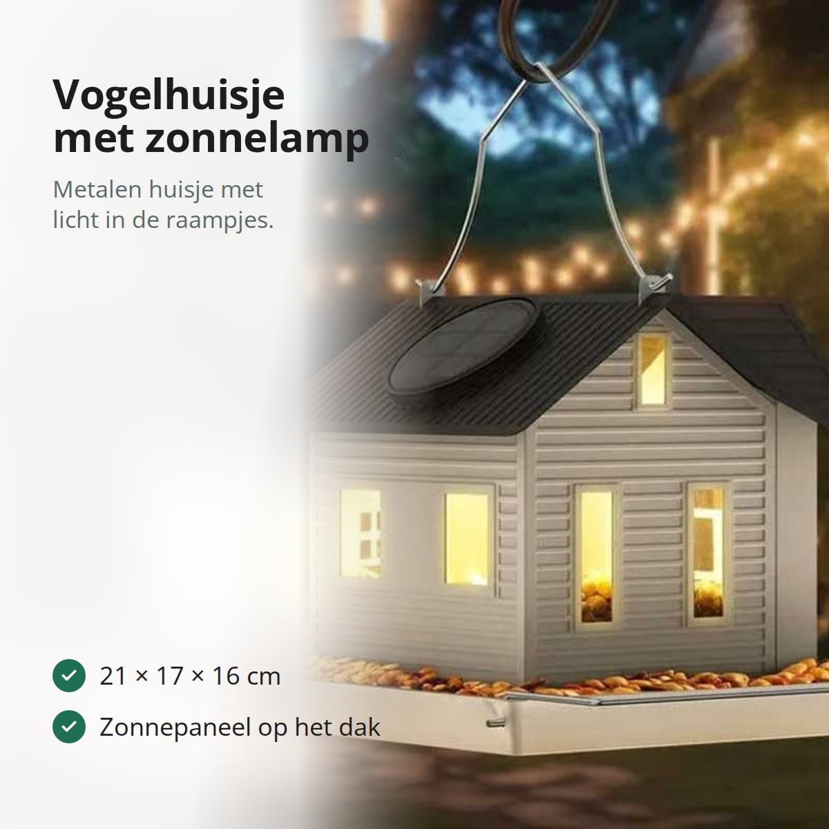 Vogelvoederhuisje in de vorm van een wit metalen huis met zwart dak, zonnepaneel en voerplankje