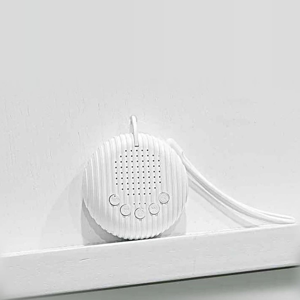 White noise machine met het koord over de rand van een wit wandplankje